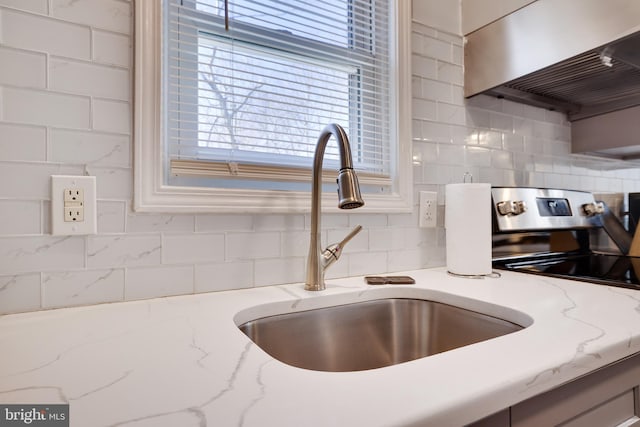 details with a sink, light stone counters, stainless steel electric range oven, exhaust hood, and decorative backsplash