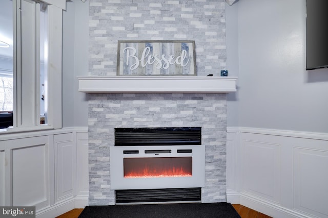 details with a wainscoted wall and a lit fireplace