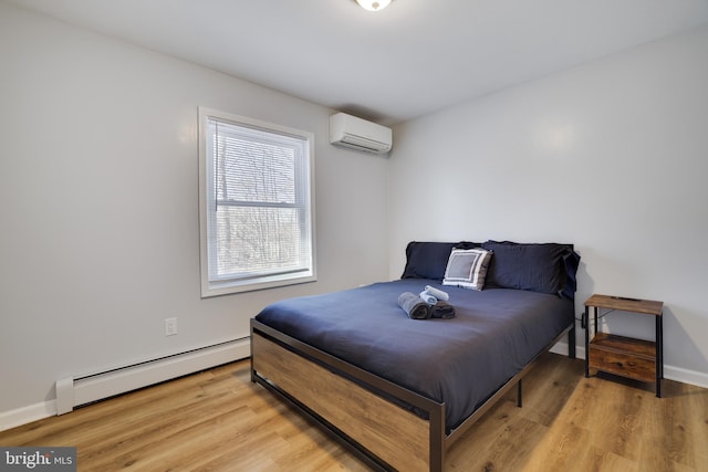 bedroom featuring light wood finished floors, baseboard heating, an AC wall unit, and baseboards