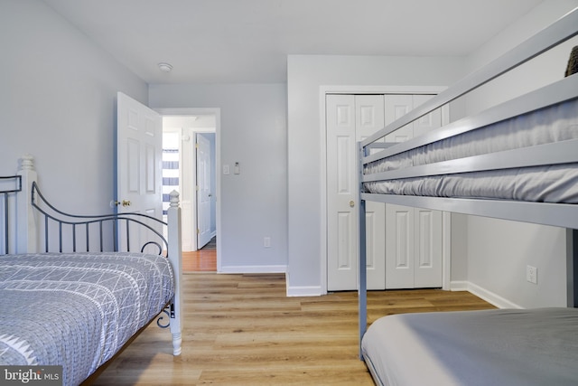 bedroom with a closet, baseboards, and light wood-style floors