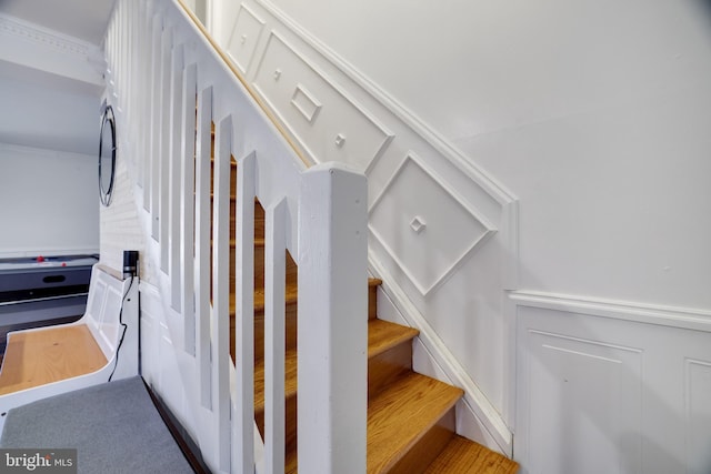 stairway with a decorative wall and a wainscoted wall