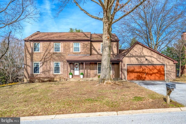 view of front of property featuring covered porch, a front lawn, a garage, aphalt driveway, and brick siding