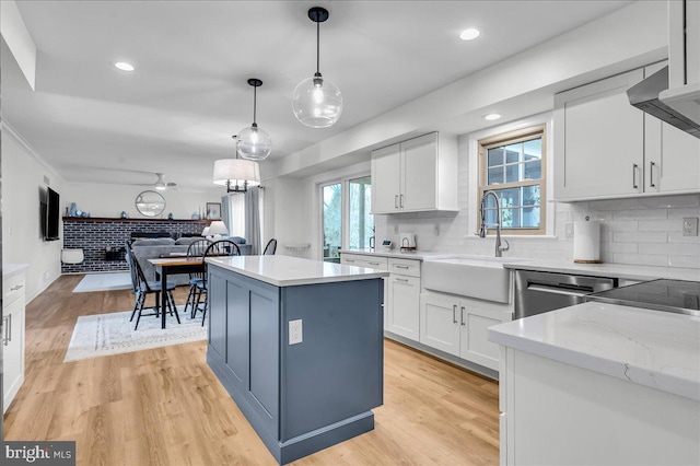 kitchen featuring a sink, light wood-style flooring, open floor plan, and white cabinetry