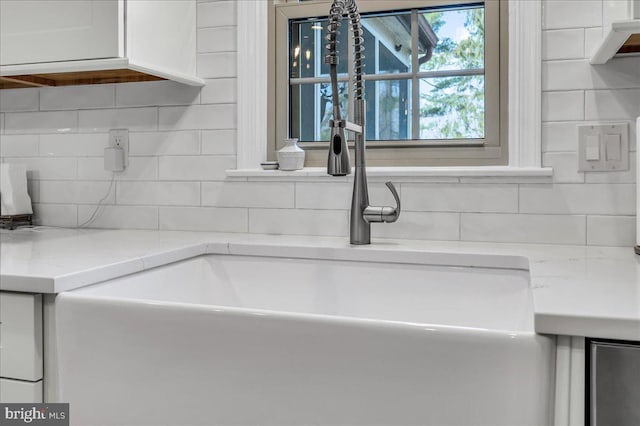 interior details featuring a sink, light stone counters, tasteful backsplash, and white cabinets