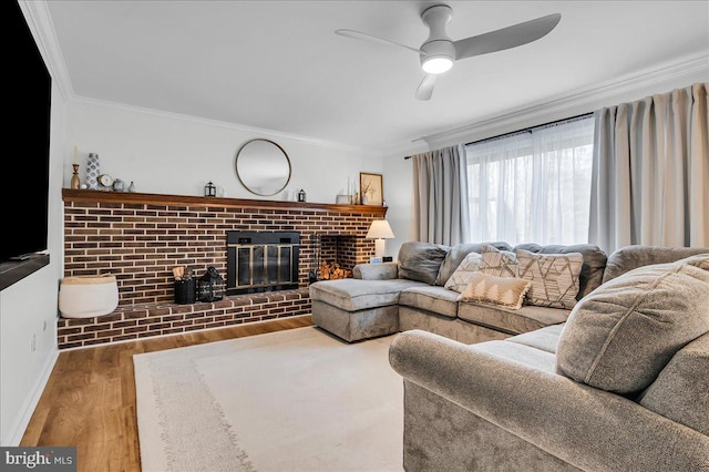 living room with a ceiling fan, wood finished floors, a fireplace, crown molding, and baseboards