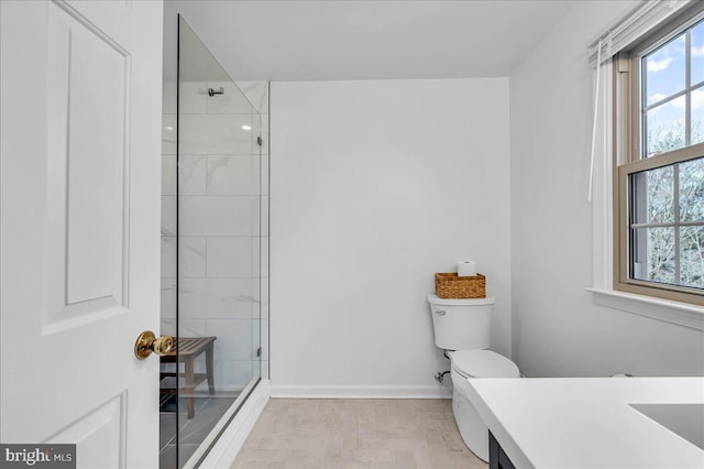 full bath with toilet, tiled shower, vanity, and baseboards