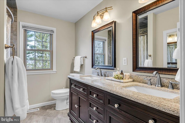 full bath featuring toilet, a wealth of natural light, and a sink