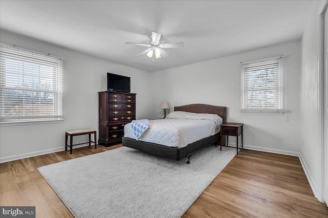 bedroom with multiple windows, wood finished floors, and baseboards