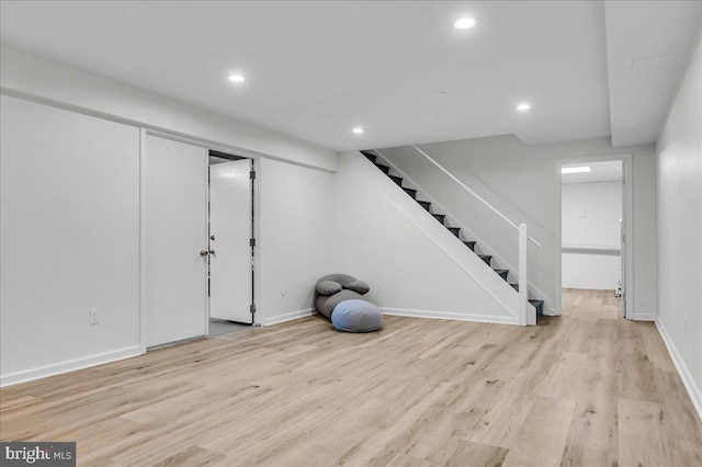 finished basement with light wood finished floors, recessed lighting, stairs, and baseboards