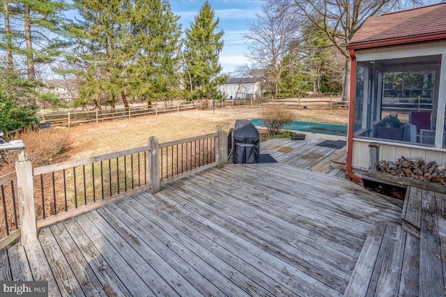 deck featuring a grill, a fenced backyard, and a sunroom