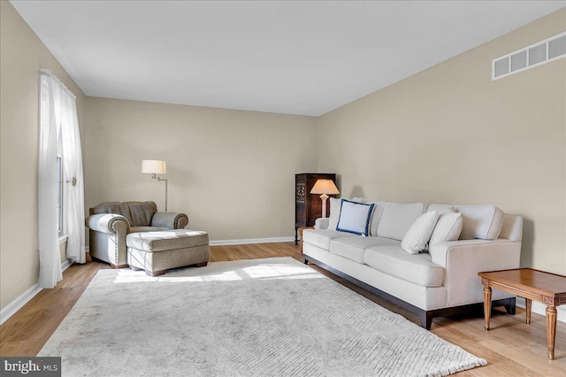 living area featuring light wood-style flooring, baseboards, and visible vents