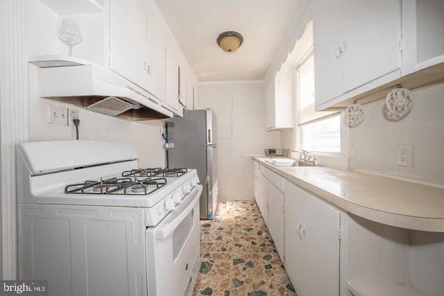 kitchen with white gas stove, freestanding refrigerator, a sink, under cabinet range hood, and white cabinetry