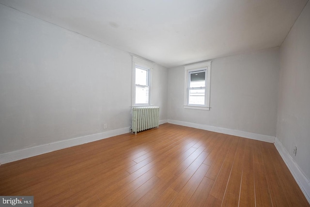 unfurnished room featuring radiator, baseboards, and hardwood / wood-style flooring