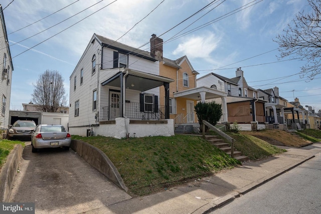 view of front of home featuring aphalt driveway, covered porch, and a chimney