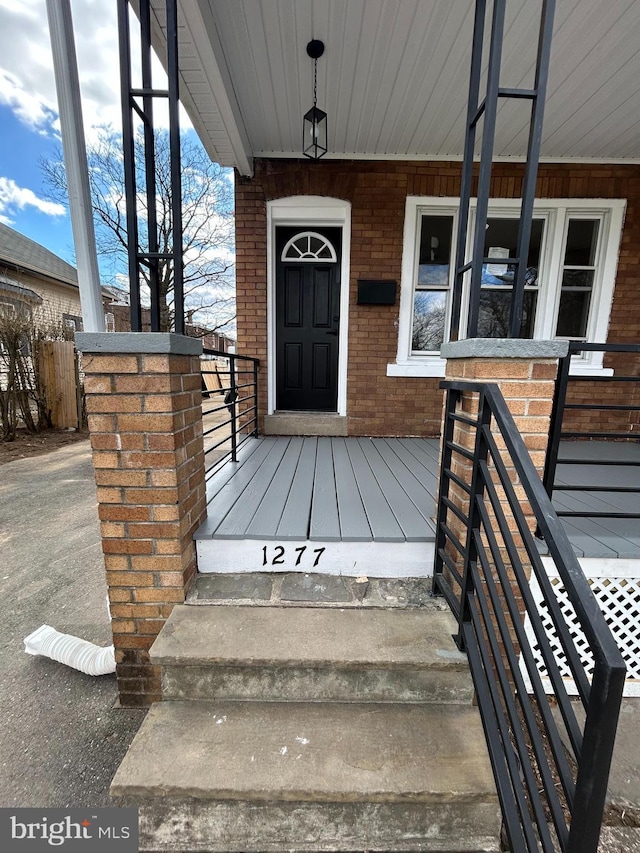 property entrance featuring brick siding and a porch