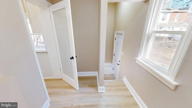 hall featuring light wood-style flooring and baseboards