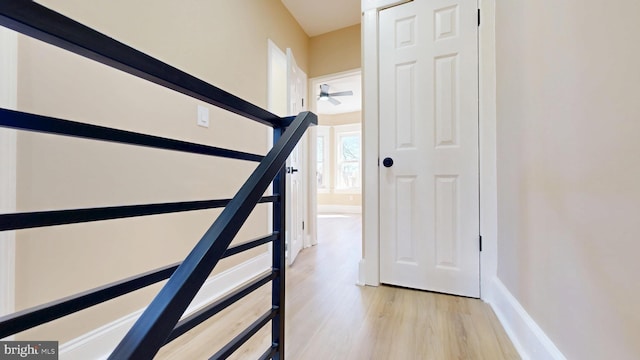 staircase featuring a ceiling fan, wood finished floors, and baseboards