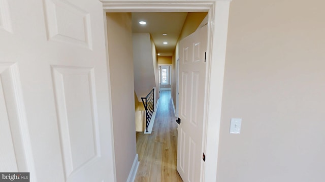 hall with recessed lighting, an upstairs landing, and light wood-type flooring