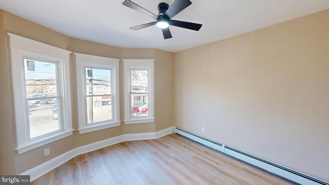 empty room featuring a baseboard heating unit, baseboards, light wood-style flooring, and a ceiling fan