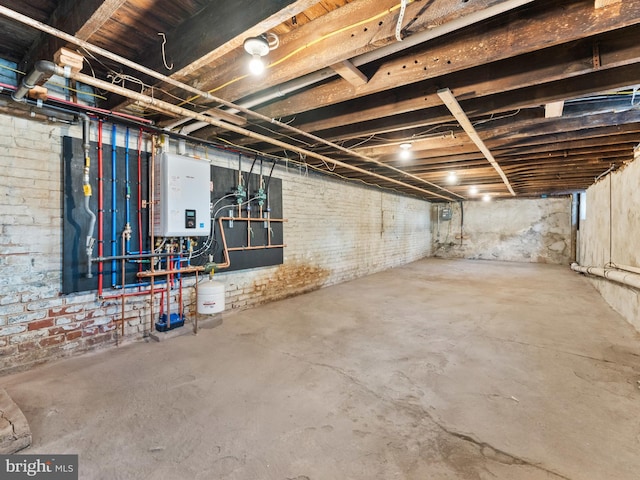 unfinished below grade area featuring tankless water heater and brick wall