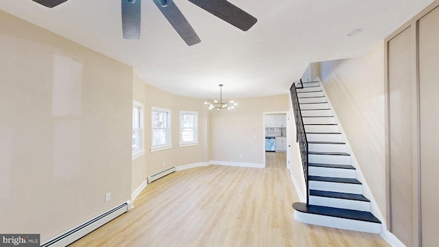 interior space featuring ceiling fan with notable chandelier, wood finished floors, baseboards, and a baseboard radiator