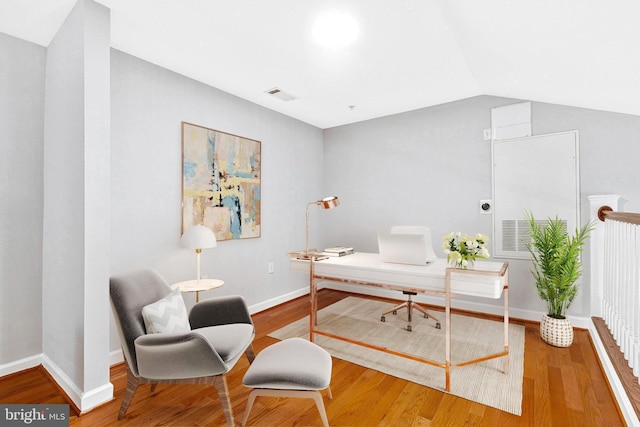 home office with vaulted ceiling, wood finished floors, visible vents, and baseboards