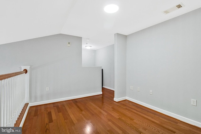 empty room with visible vents, baseboards, lofted ceiling, and wood finished floors