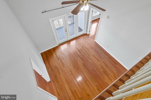 unfurnished living room with ceiling fan, french doors, baseboards, and light wood-style floors