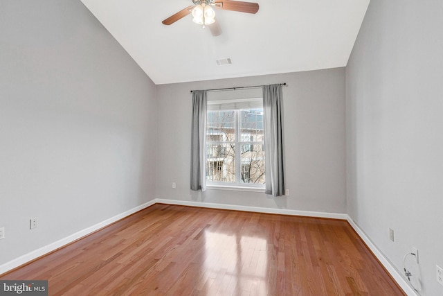 spare room with visible vents, baseboards, vaulted ceiling, wood finished floors, and a ceiling fan