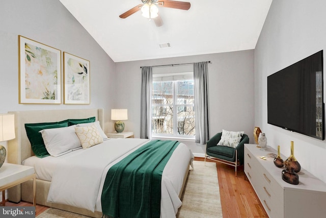 bedroom featuring visible vents, light wood-style flooring, a ceiling fan, and vaulted ceiling