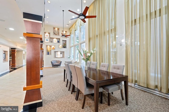 carpeted dining space featuring baseboards, ceiling fan, recessed lighting, a high ceiling, and tile patterned floors