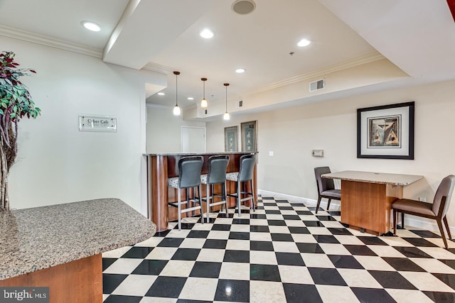 interior space featuring visible vents, baseboards, a breakfast bar, ornamental molding, and recessed lighting