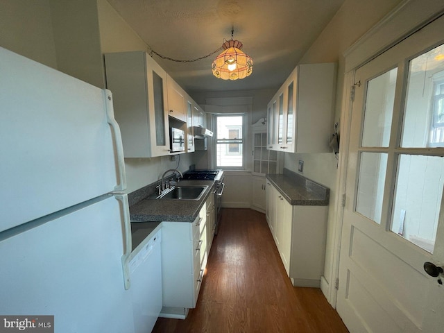 kitchen with dark countertops, white cabinetry, stainless steel appliances, and a sink