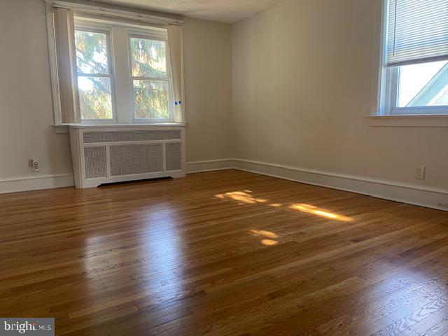 empty room with radiator, baseboards, and wood finished floors