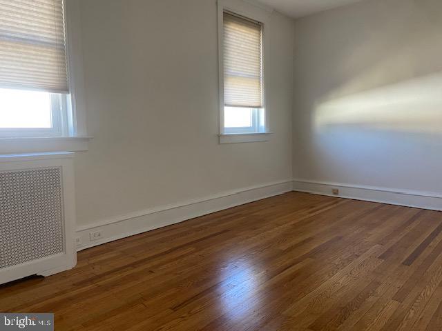 empty room with baseboards, radiator, and wood finished floors