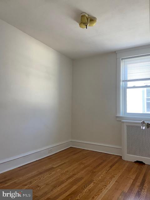 empty room featuring baseboards, radiator, and wood finished floors