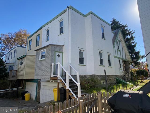 exterior space with stucco siding, an attached garage, and fence