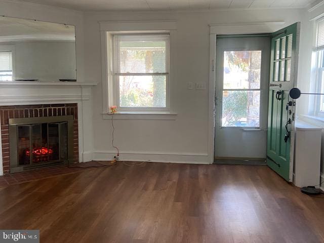 unfurnished living room with wood finished floors, crown molding, and a fireplace