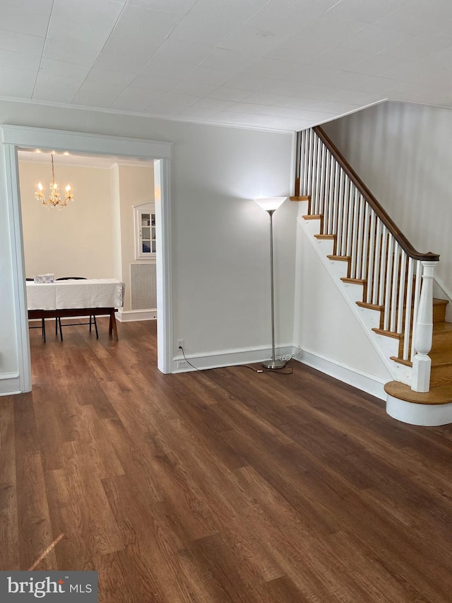 interior space featuring a notable chandelier, stairway, baseboards, and wood finished floors