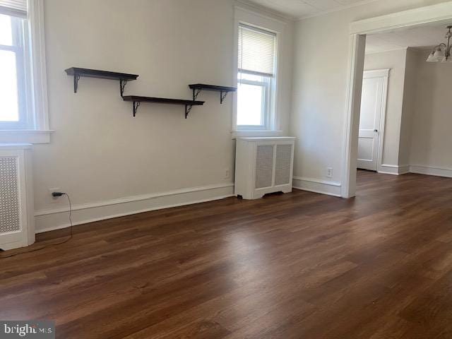 empty room with radiator heating unit, wood finished floors, and baseboards