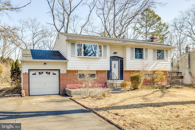 split foyer home with driveway, a shingled roof, a garage, brick siding, and a chimney