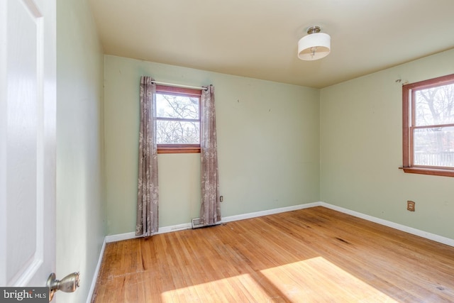 spare room with plenty of natural light, baseboards, and wood finished floors