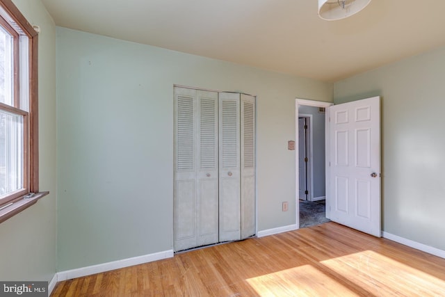 unfurnished bedroom featuring light wood-type flooring, multiple windows, and baseboards