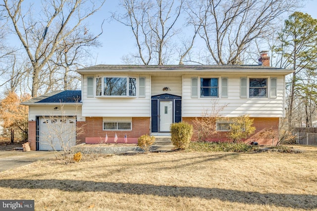 split foyer home with a garage, brick siding, concrete driveway, and a chimney