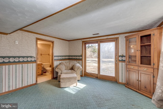 sitting room featuring visible vents, wallpapered walls, ornamental molding, a textured ceiling, and light carpet