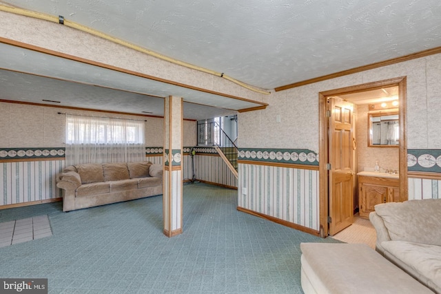 carpeted living area featuring baseboards, a textured ceiling, ornamental molding, and wallpapered walls