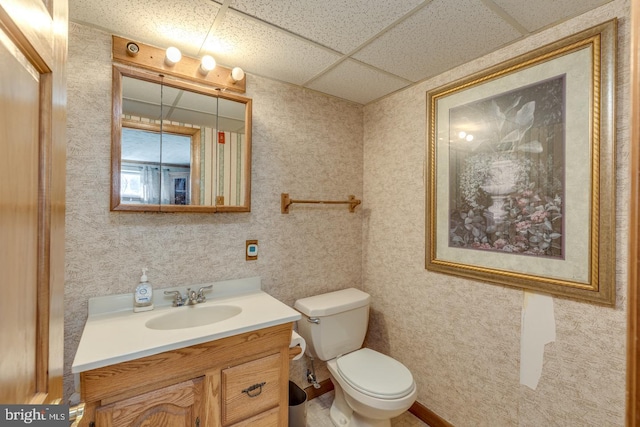 bathroom with a paneled ceiling, toilet, and vanity