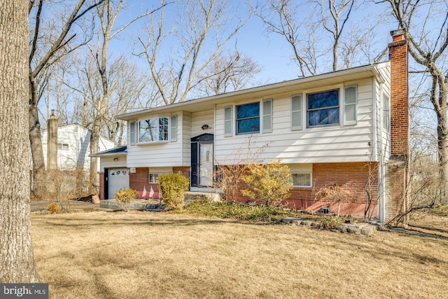 split foyer home with a front lawn, a garage, brick siding, and a chimney