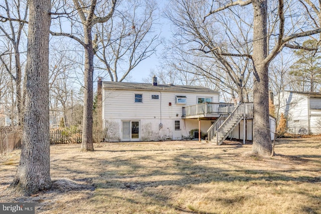 back of house with a wooden deck, a lawn, a chimney, and stairs