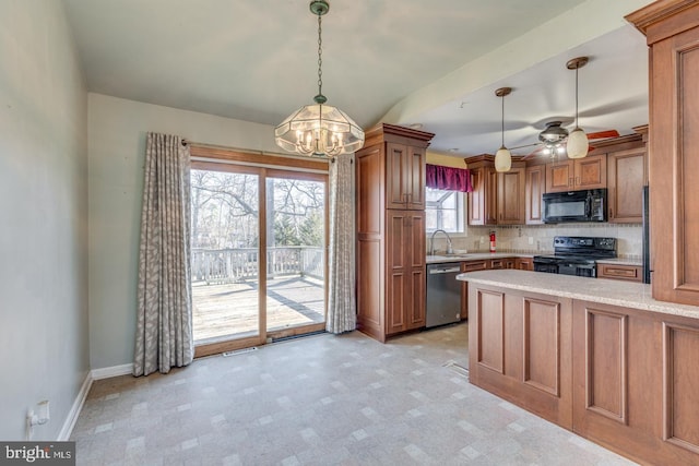 kitchen featuring baseboards, ceiling fan with notable chandelier, brown cabinets, black appliances, and a sink